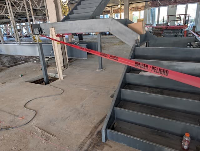 The steel feature stair standing on the slab, a landing and a second flight above, taped off