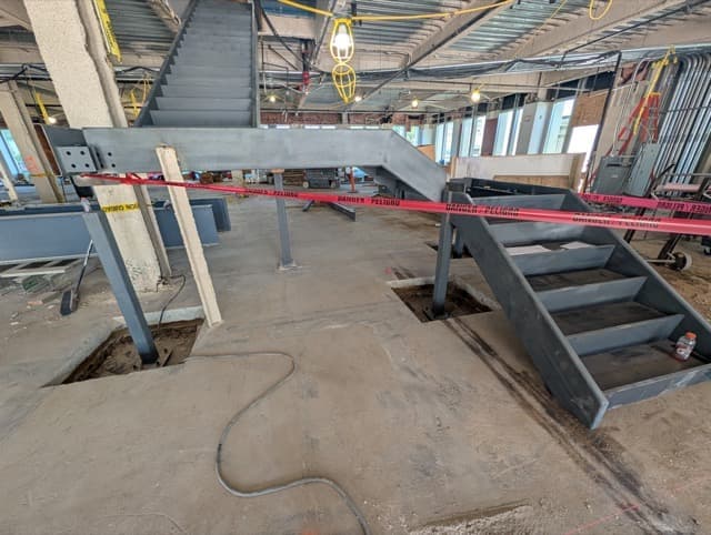 The feature stair from further back, its flights rising to the floor above an open floor plate